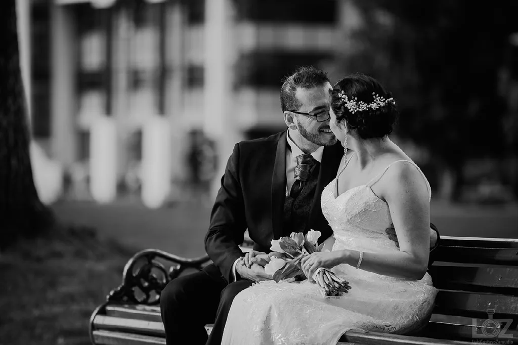 Retrato en blanco y negro de los novios sentados en una banca de plaza tras su matrimonio civil