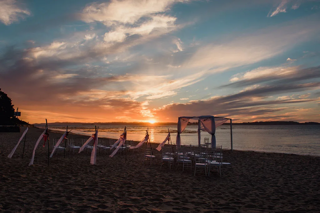 Altar y sillas de una ceremonia de matrimonio en la playa al atardecer, Región del Biobío