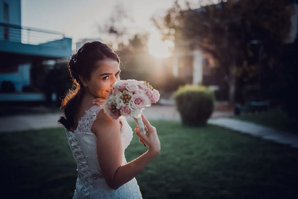 Novia jugando con su ramo de flores a contraluz del atardecer