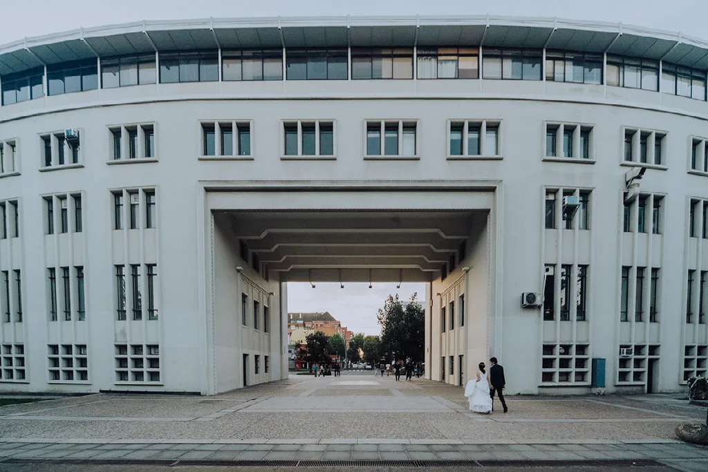 Novios caminando bajo el Arco de la Universidad de Concepción en su sesión de matrimonio