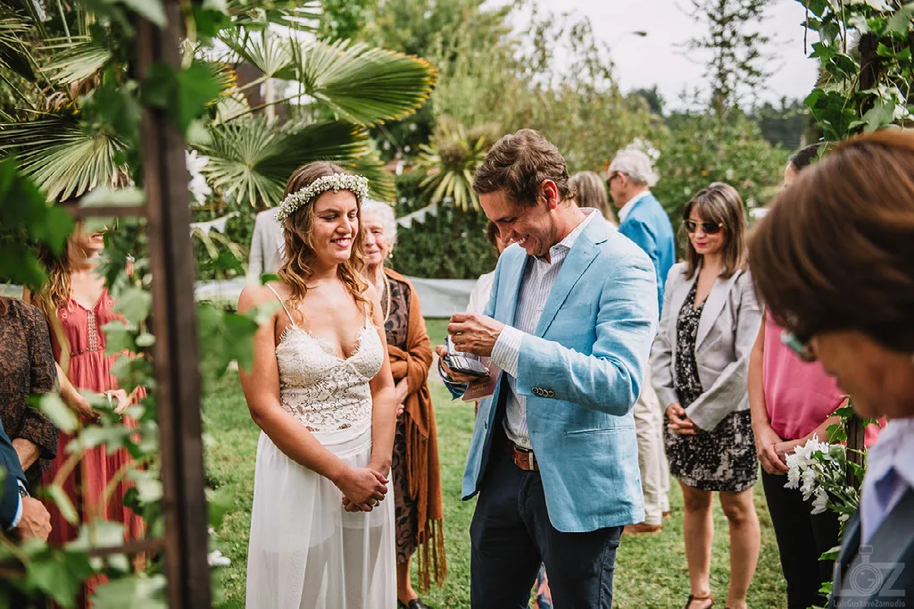 Novia sonriendo durante la ceremonia de matrimonio al aire libre entre sus invitados