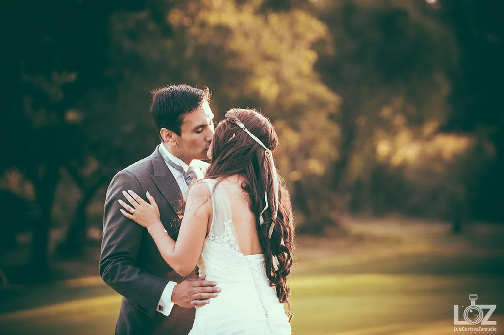 Beso de los novios en el parque con la luz dorada del atardecer