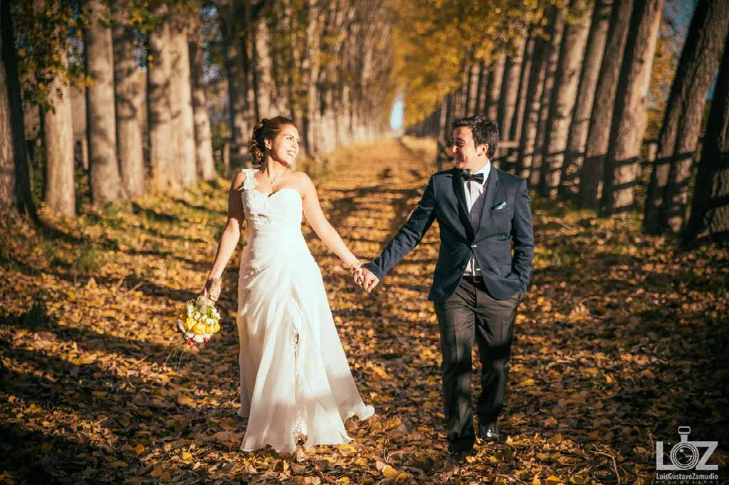 Novios caminando de la mano por una alameda en otoño durante su sesión preboda