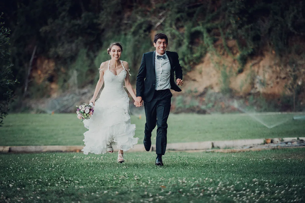 Novios corriendo por el pasto en su sesión de fotos de matrimonio
