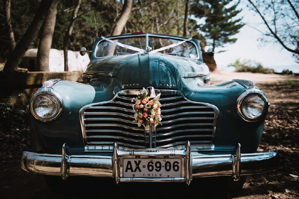 Frontis del auto clásico de los novios decorado con flores