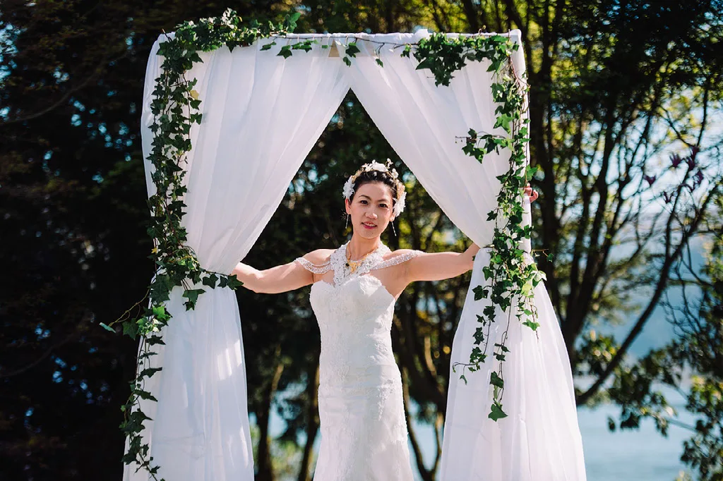 Novia asomándose por el arco de telas y flores de la ceremonia
