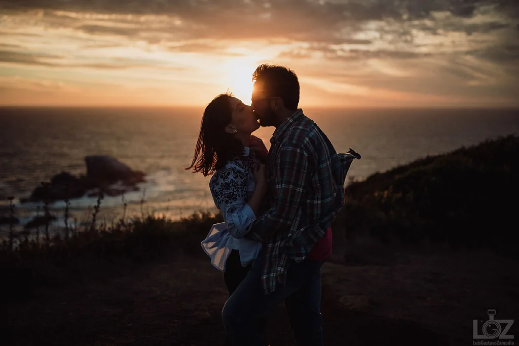 Beso de la pareja a contraluz del atardecer sobre el mar en su sesión preboda