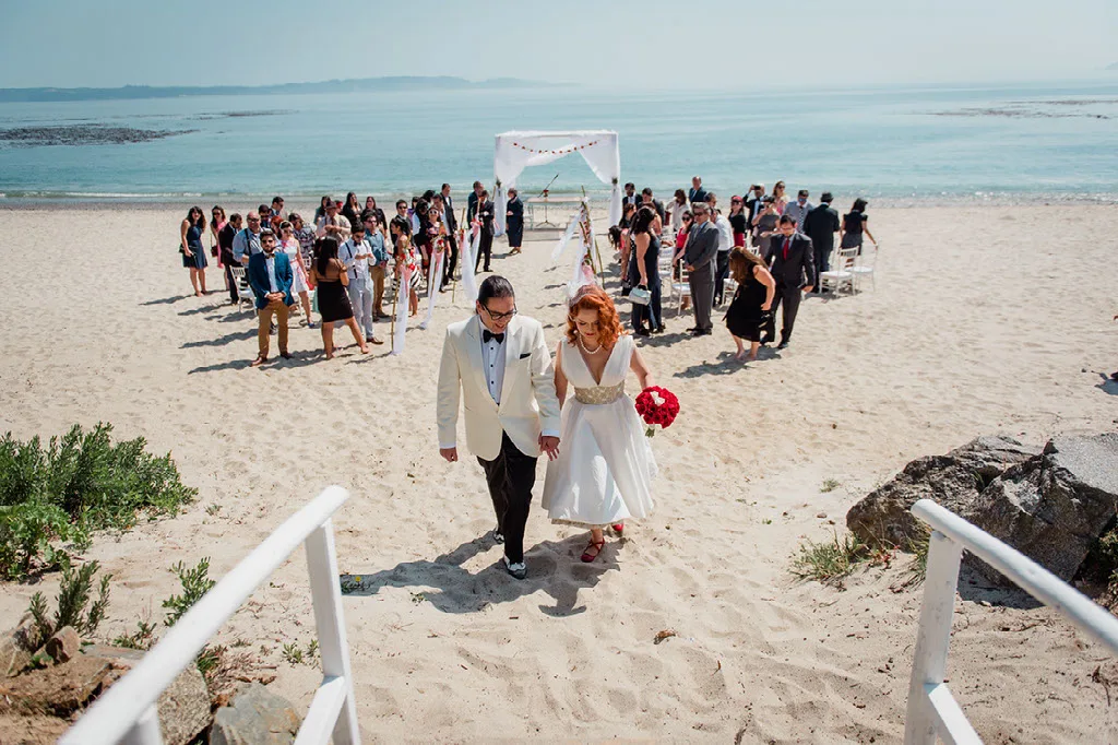Novios caminando por la arena tras su ceremonia de matrimonio en la playa