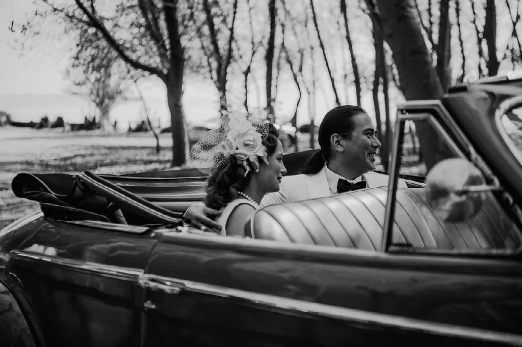 Novios conversando en el auto clásico descapotable, blanco y negro