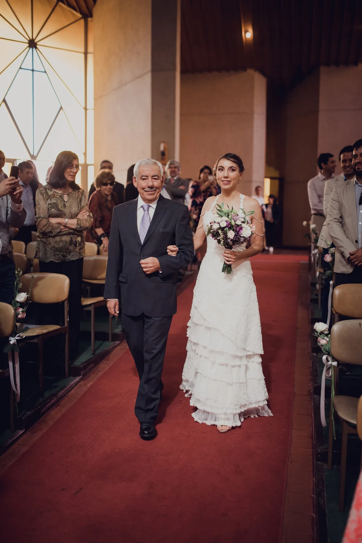 La novia entra del brazo por el pasillo de la iglesia